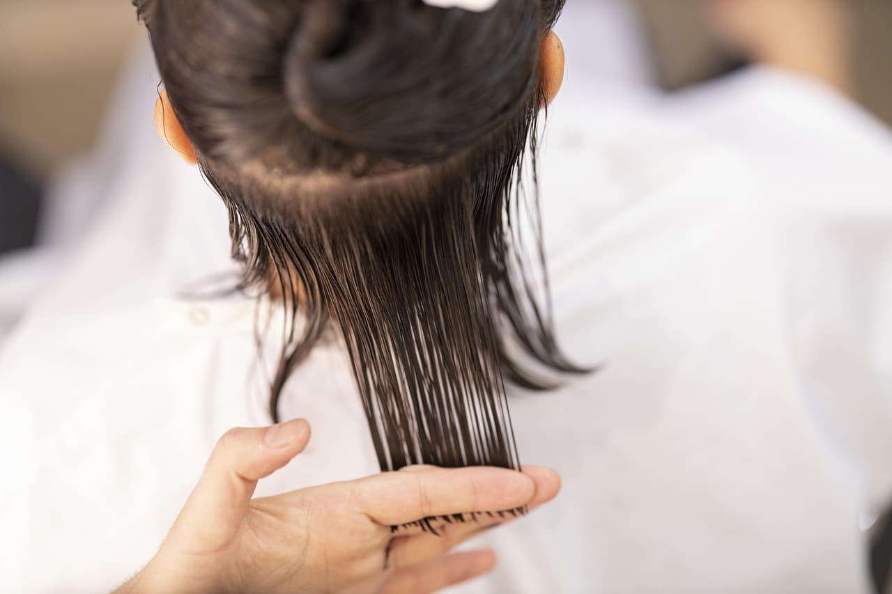 A hairdresser combing through a client's long dark hair