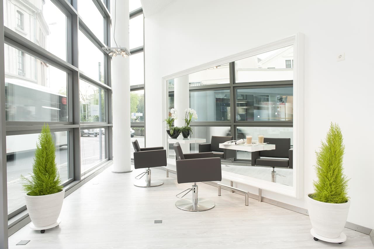 A light salon with tall windows, mirrors and styling chairs