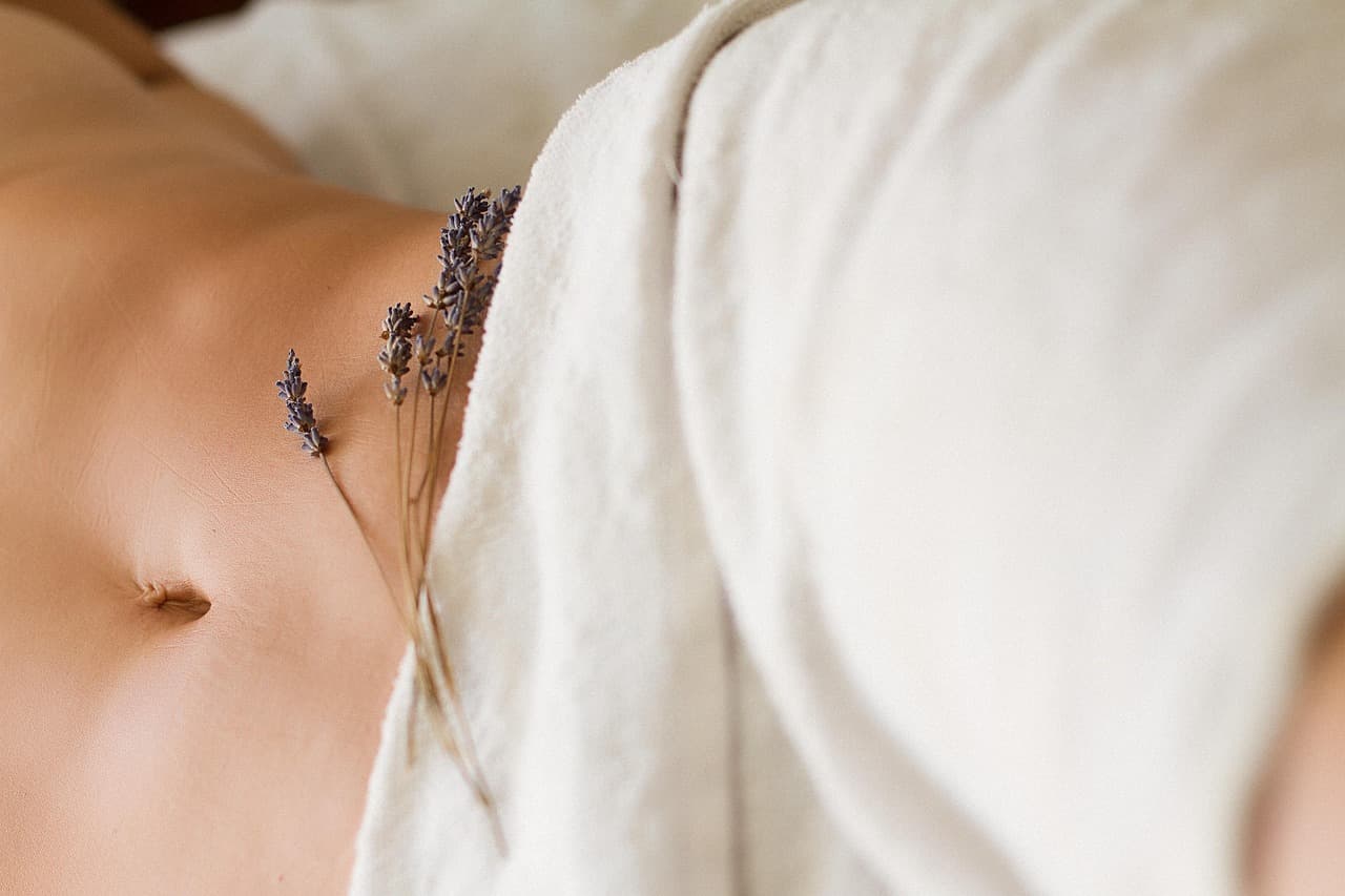 A client lying under a soft white towel on a treatment bed