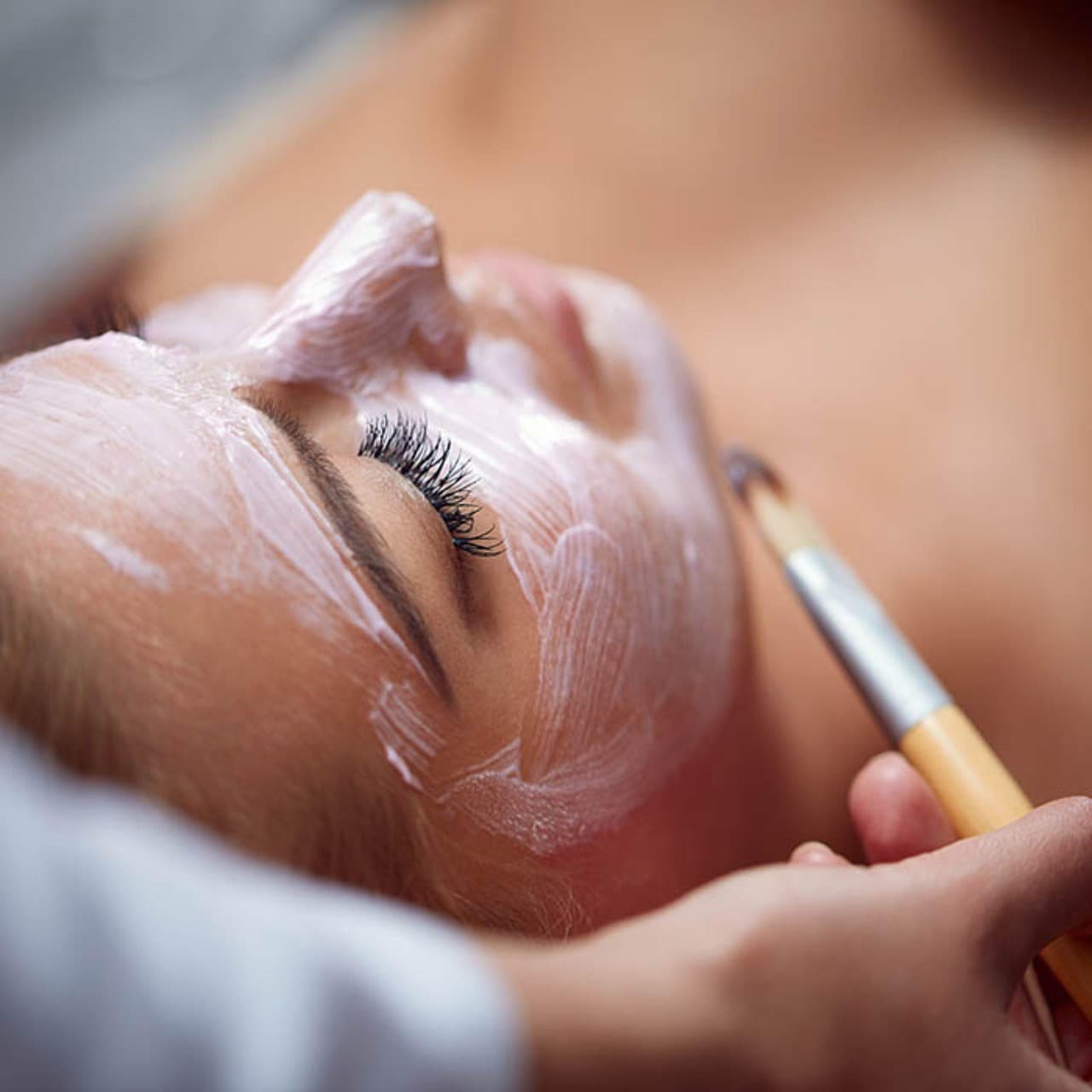 A facial mask brushed onto a client's skin
